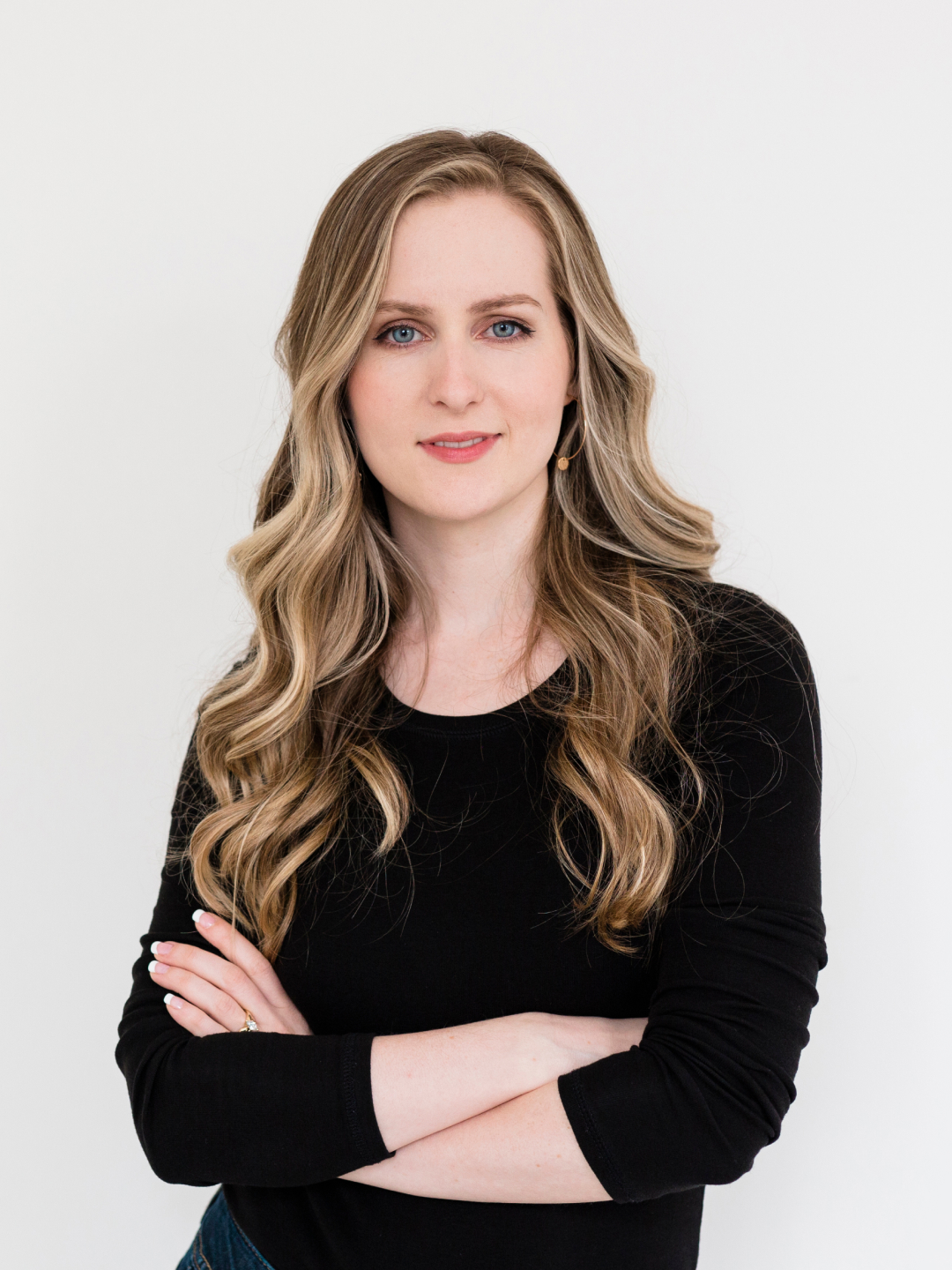 Portrait of Gillian in a black top, standing with her arms crossed against a white background.