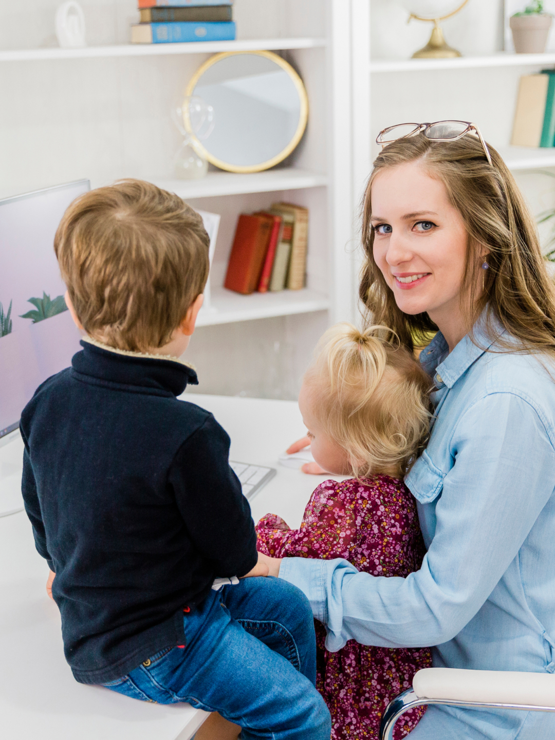 Gillian at a computer with two of her young children beside her.